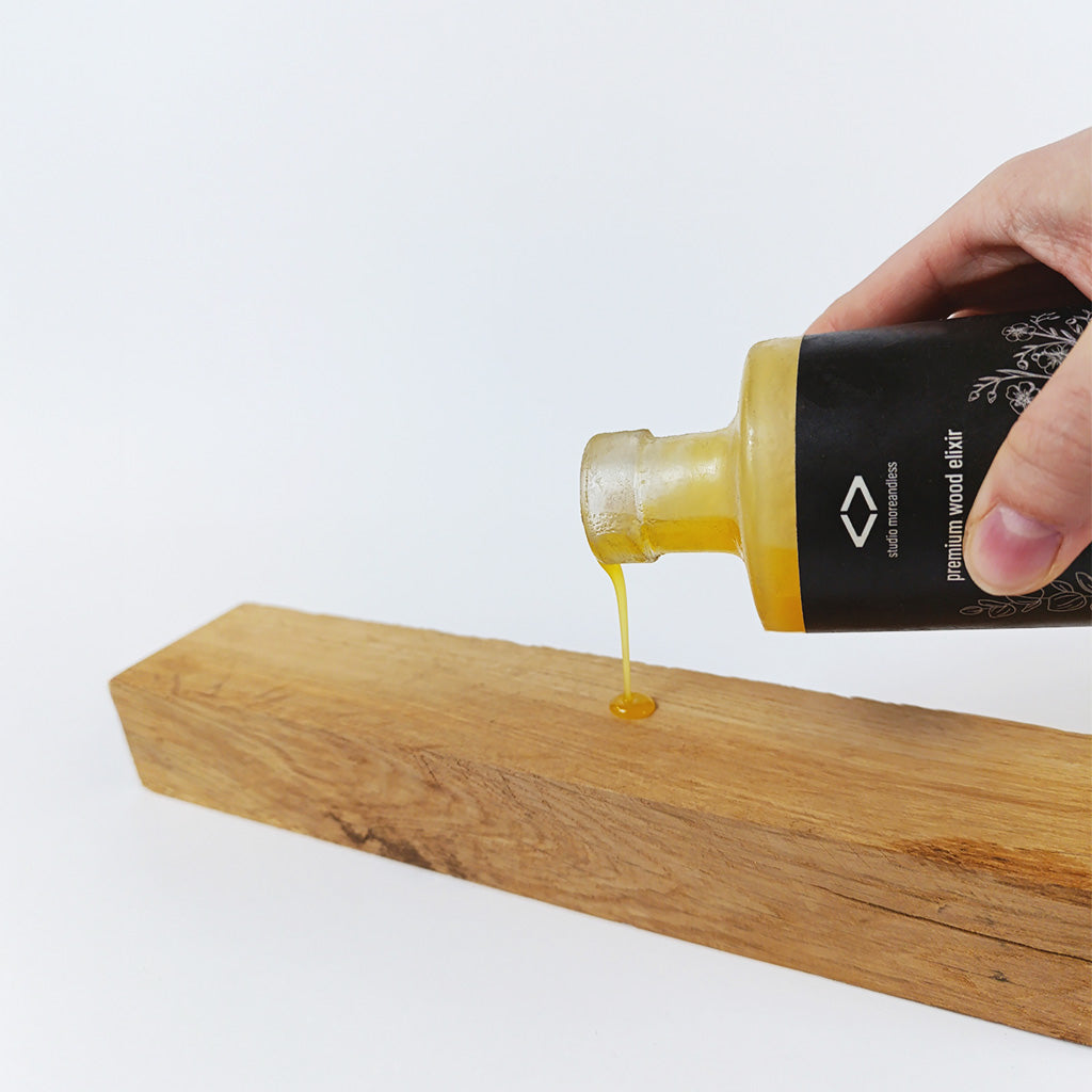 Einzelner Tropfen premium wood elixir auf Holz – natürliches, veganes Holzöl für gezielte, sanfte Anwendung und Tiefenpflege