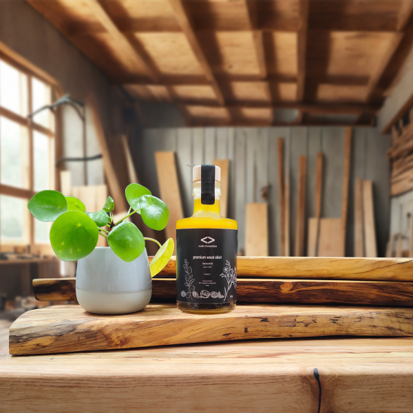 premium wood elixir 200ml auf bretterstapel in werkstatt mit pflanze nachhaltige Holzpflege aus 100% natürlichen Inhaltsstoffen. studio moreandless