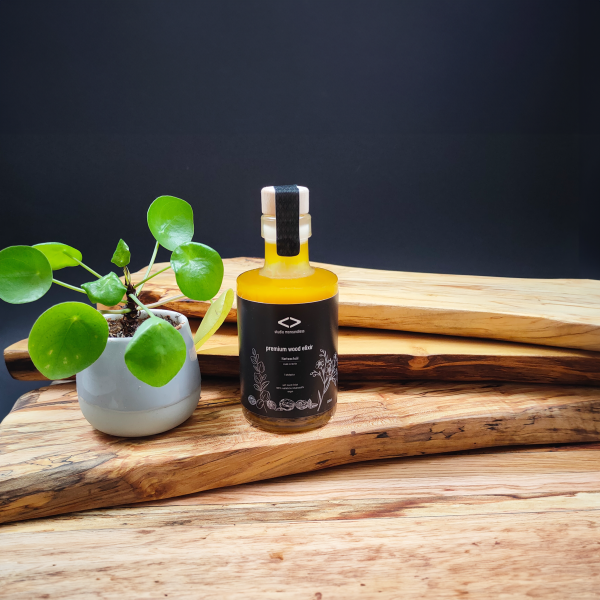 premium wood elixir 200ml auf bretterstapel mit pflanze nachhaltige Holzpflege aus 100% natürlichen Inhaltsstoffen. studio moreandless